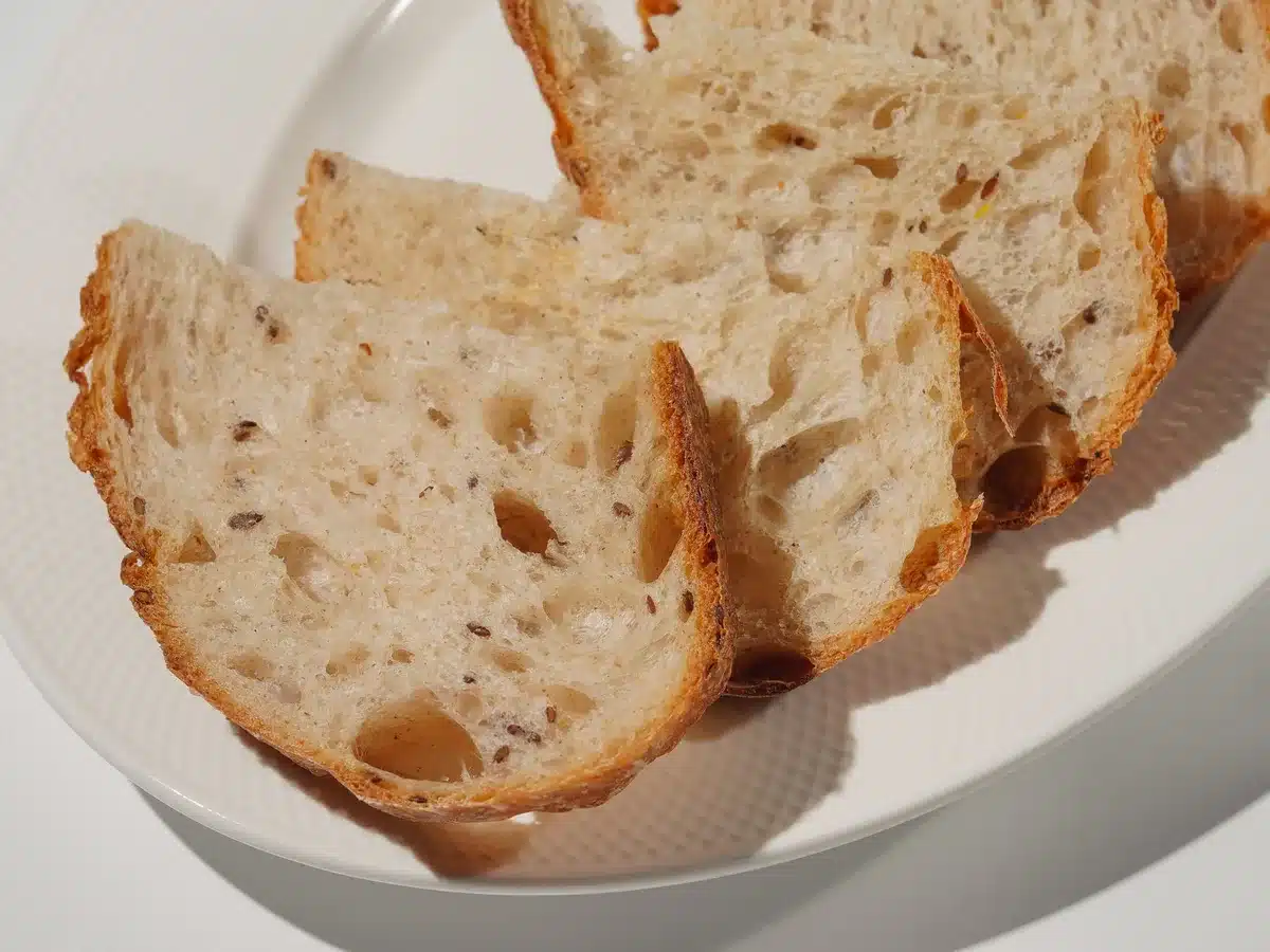 Piatto con pane integrale, pasta, cioccolato e verdure fresche su tavolo luminoso