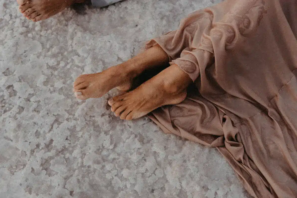 Dettaglio dei piedi che affondano nella sabbia durante un esercizio di equilibrio