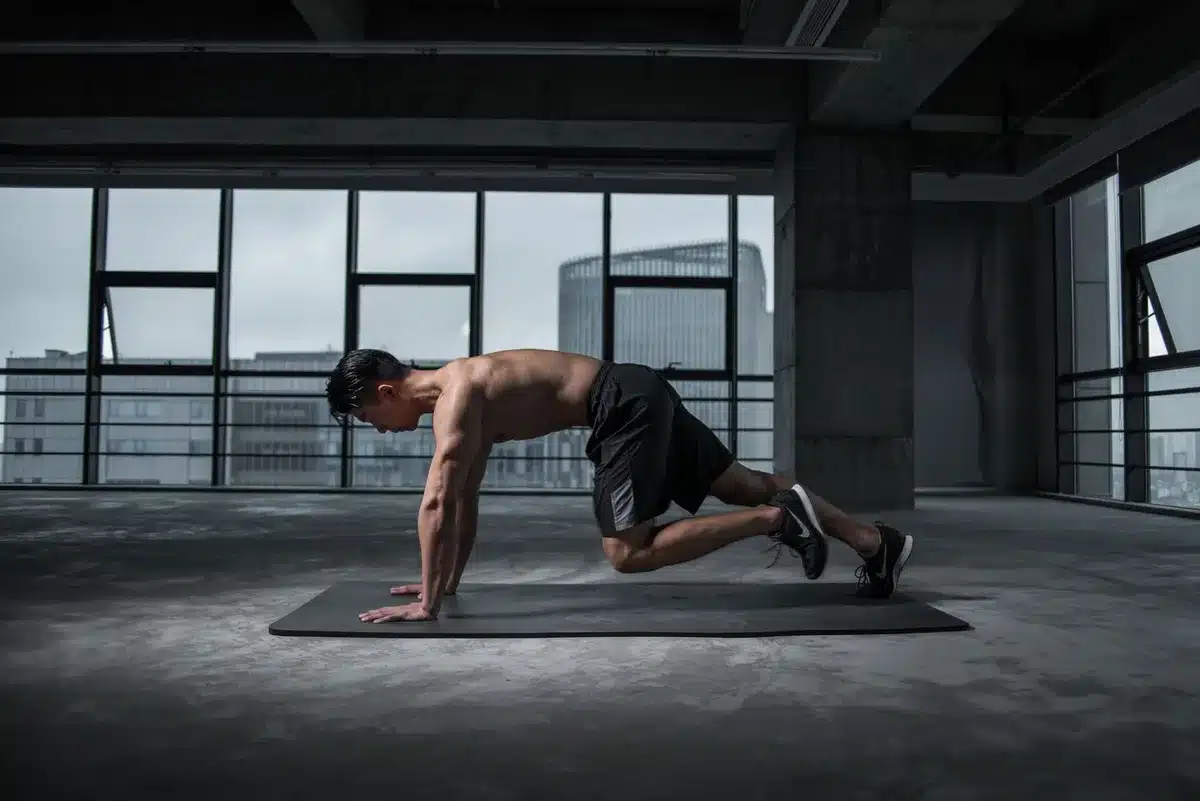 Persona in posizione plank che esegue mountain climber con le ginocchia alternate al petto