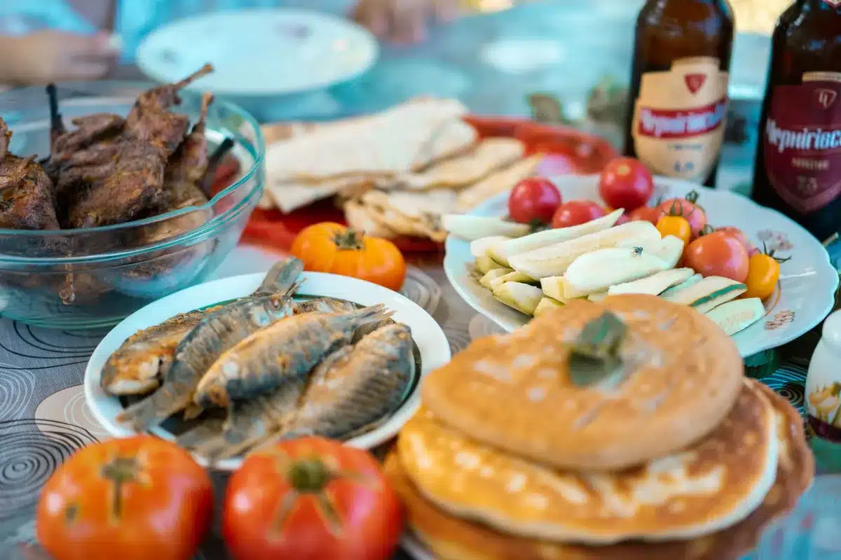 Tavolo da pranzo estivo con piatti di verdure grigliate, pesce e bevande, momento di convivialità
