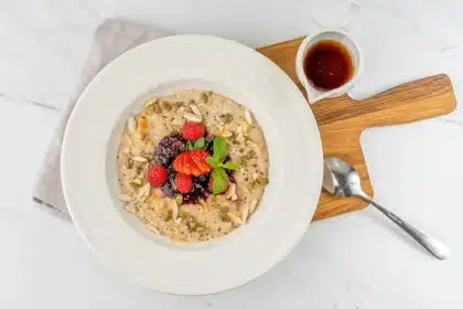 Ciotola di porridge cremoso con frutti di bosco, noci e miele su tavolo da colazione