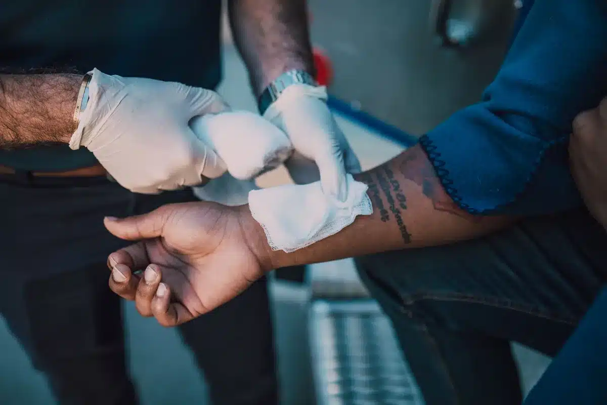 Mano di una persona con ferita medicata prima di entrare in acqua al mare.
