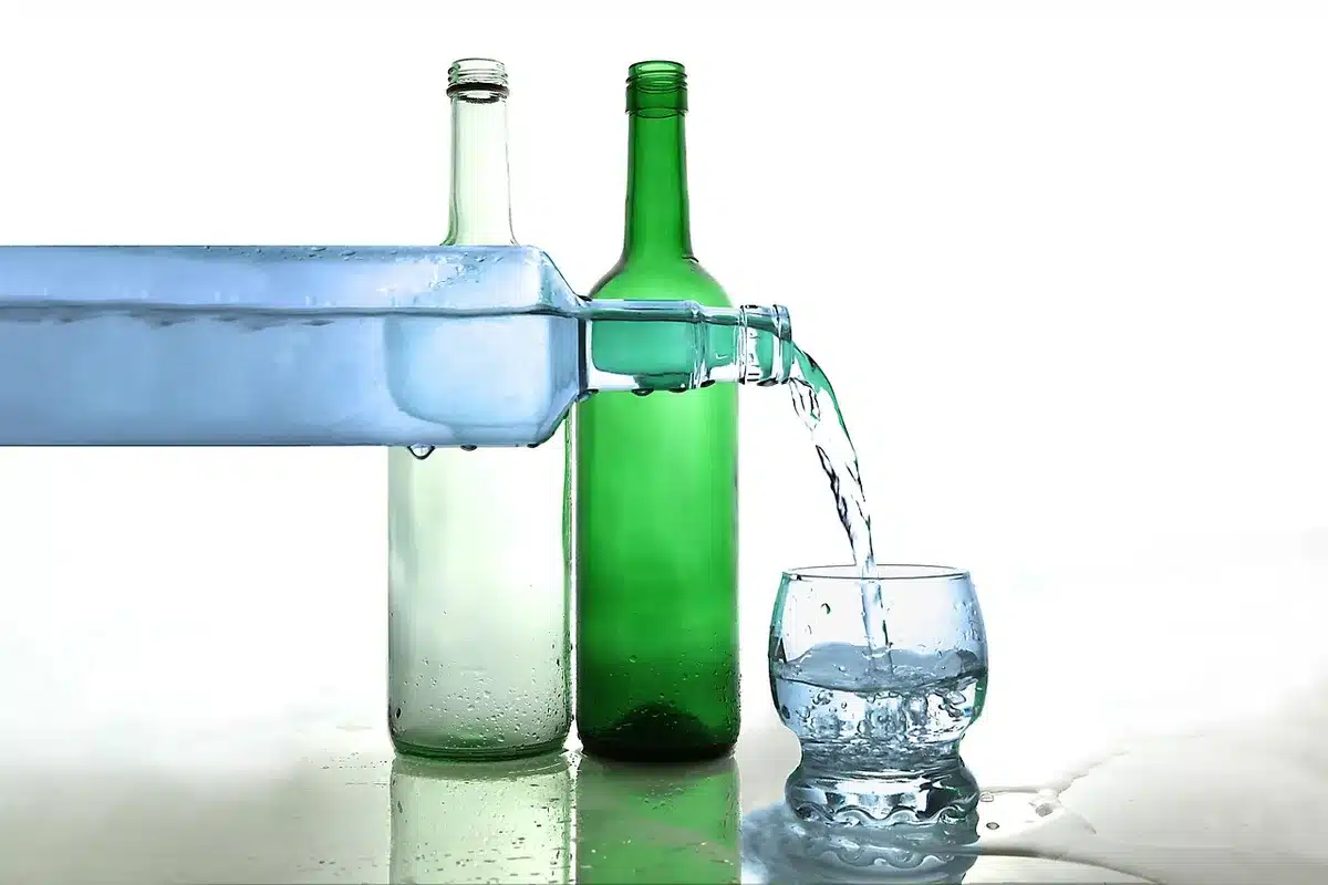 Donna che esegue curl con bottiglie d'acqua in uno spazio aperto soleggiato.