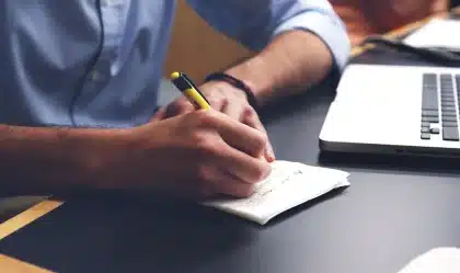 Mani anonime su una scrivania con immagini cerebrali sfocate e libri