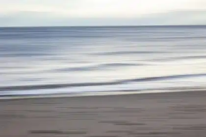 Piedi nudi su spiaggia accanto a tappetino da allenamento e borraccia al mattino