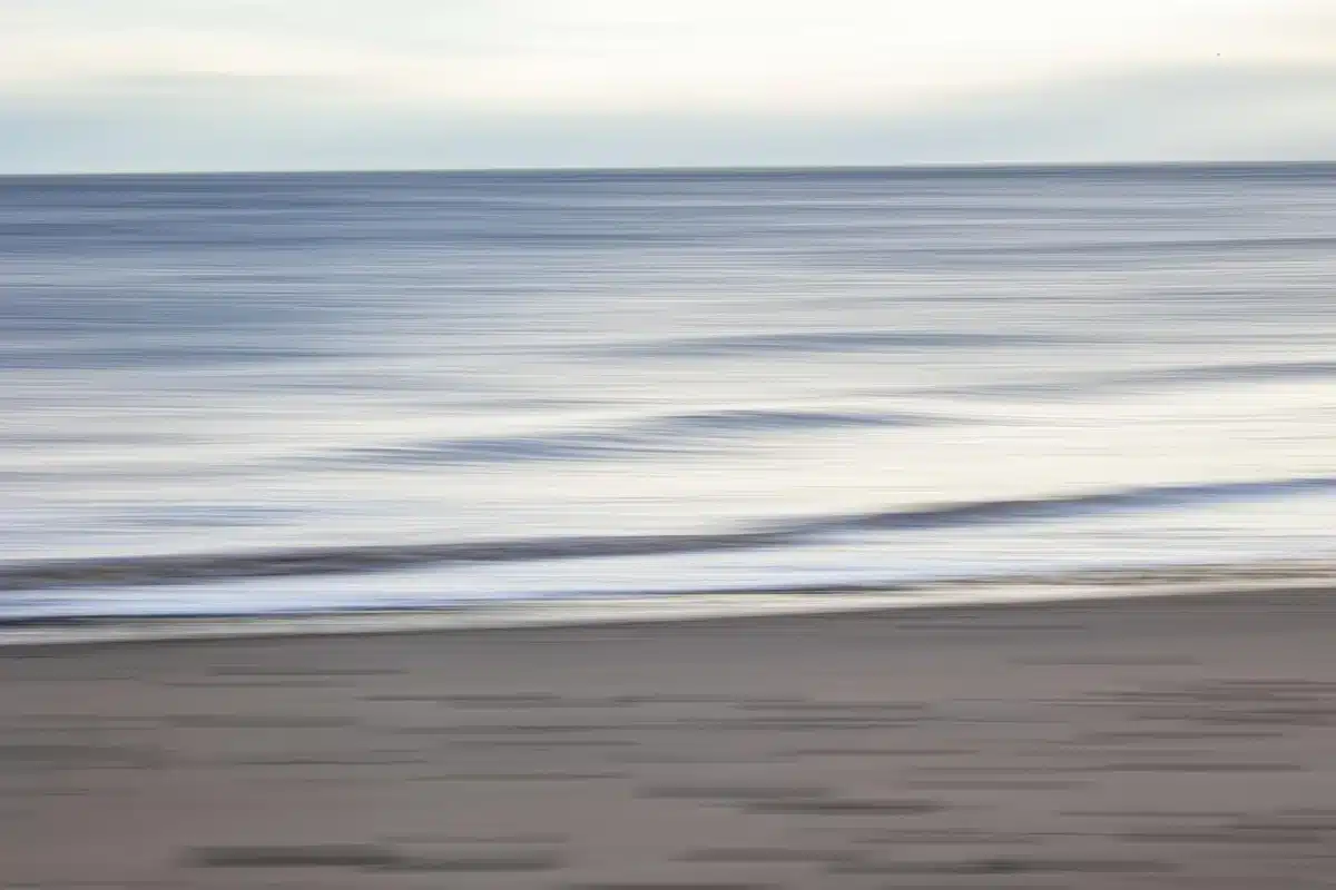 Piedi nudi su spiaggia accanto a tappetino da allenamento e borraccia al mattino