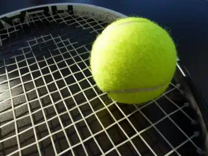 Bordo campo da tennis con racchetta e ginocchiera appoggiate, luce soft