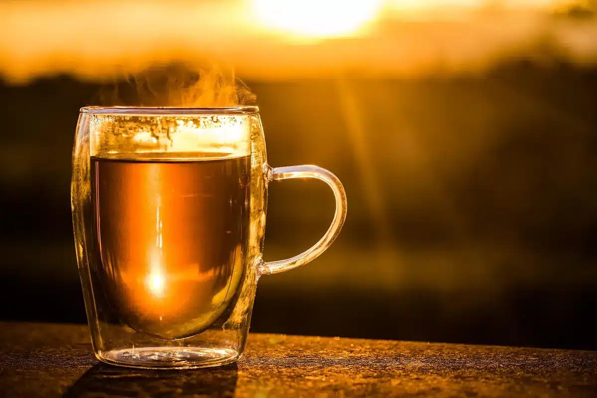 Tazza calda su tavolo con foglie autunnali che evoca cambio di stagione