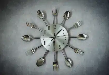 Piatto semplice, bicchiere d'acqua e orologio da tavolo che indica la sera