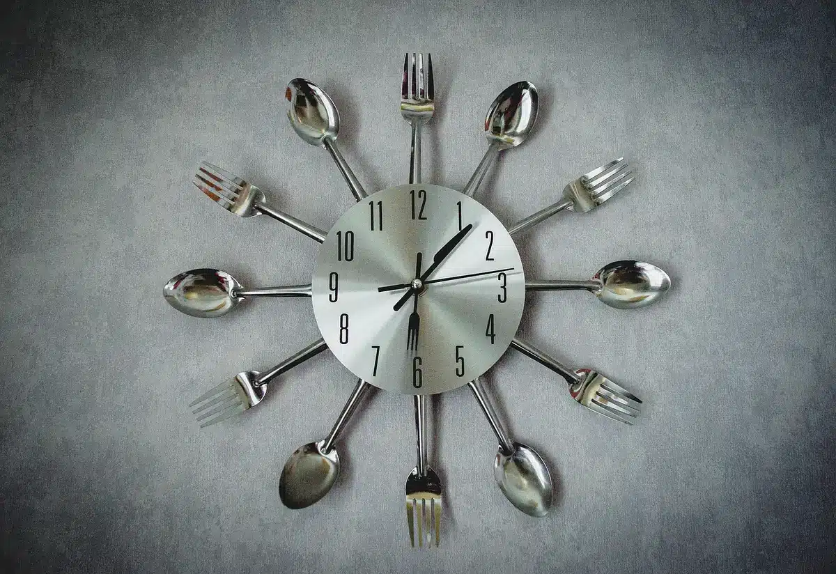 Piatto semplice, bicchiere d'acqua e orologio da tavolo che indica la sera