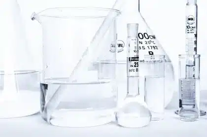 Mani guantate tengono una provetta in laboratorio con fiale sullo sfondo