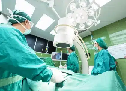Mani che tengono un modulo di consenso su un tavolo in ospedale, ambiente clinico sfocato