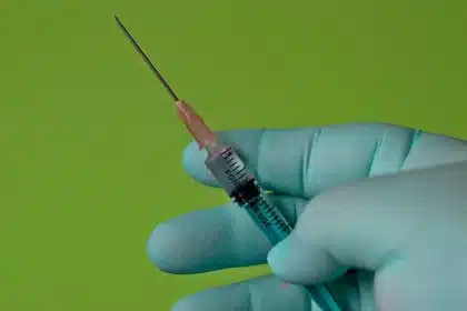 Mano che indica una data su un calendario accanto a una tessera vaccinale e una mascherina